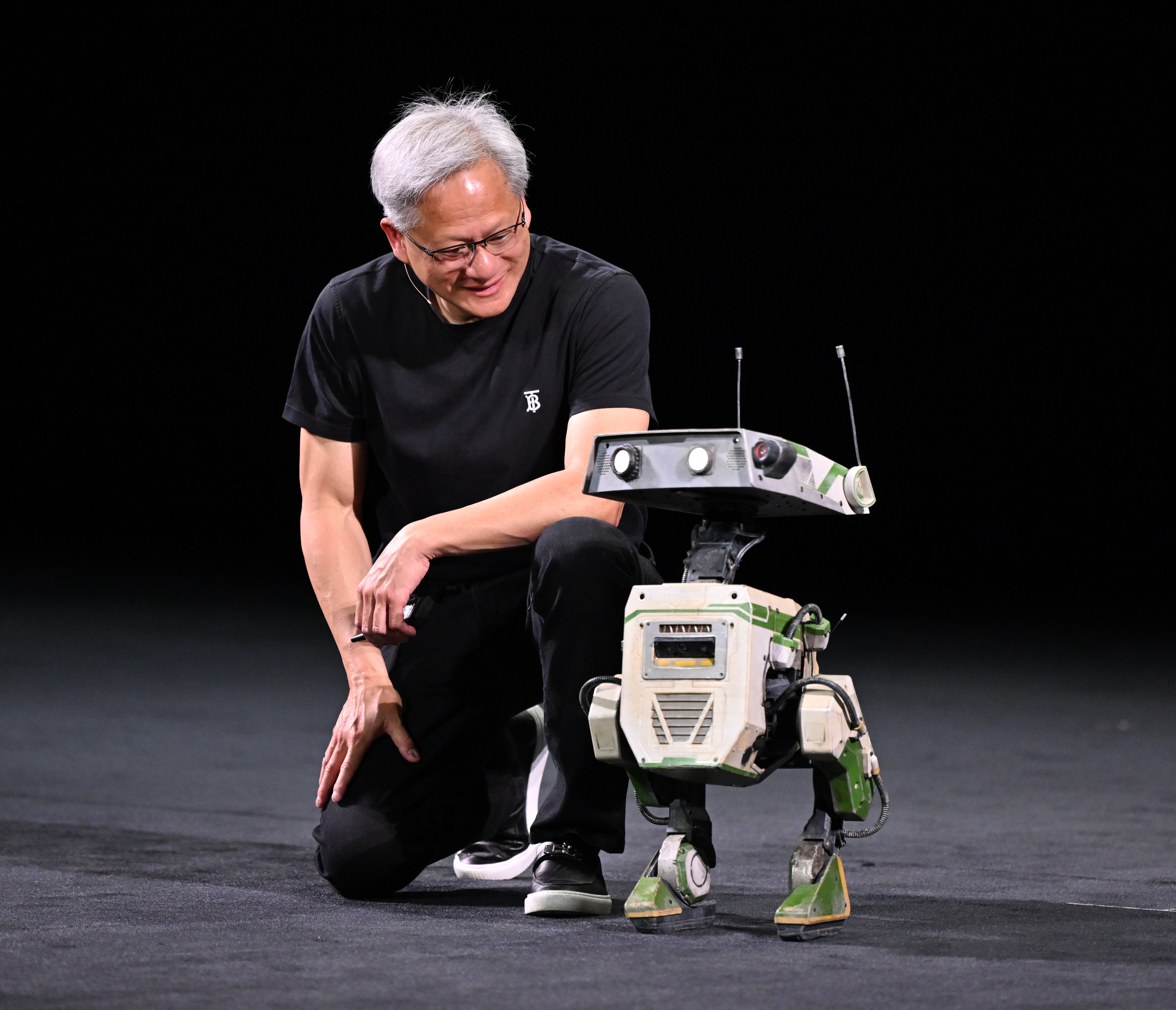 Jensen Huang kneeling next to a robot.