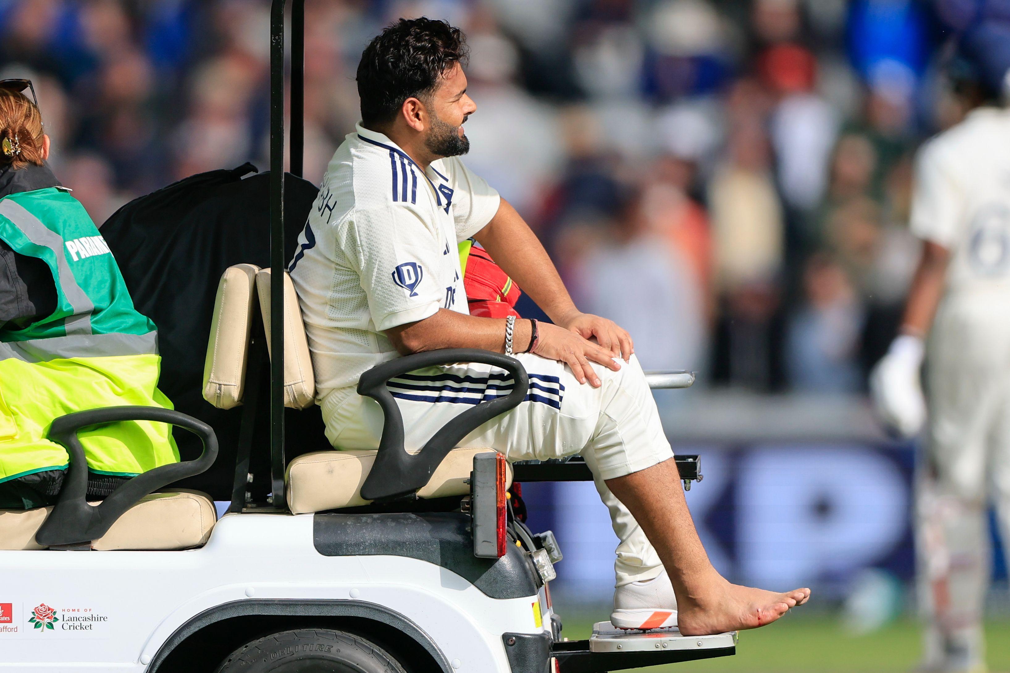 Rishabh Pant of India leaves the field after being hit on the foot during a cricket match.