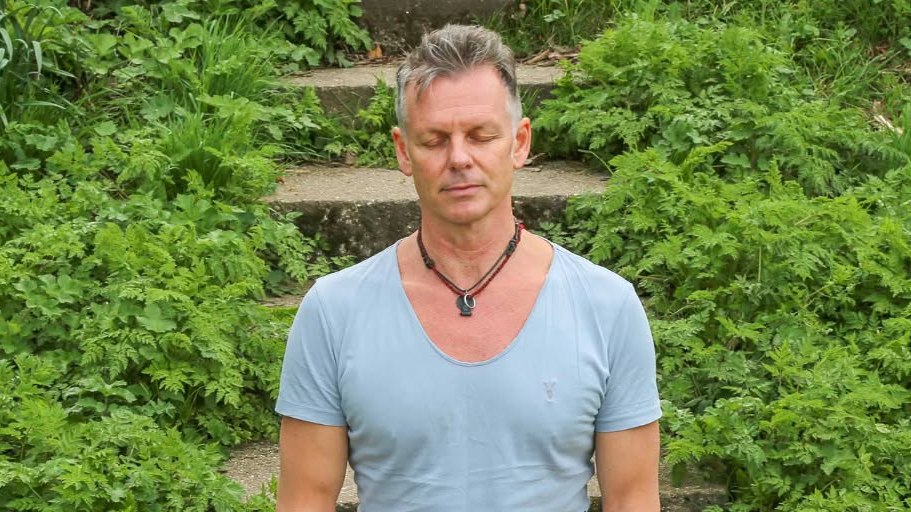 Yoga guru Jamie Clarke meditating outdoors.