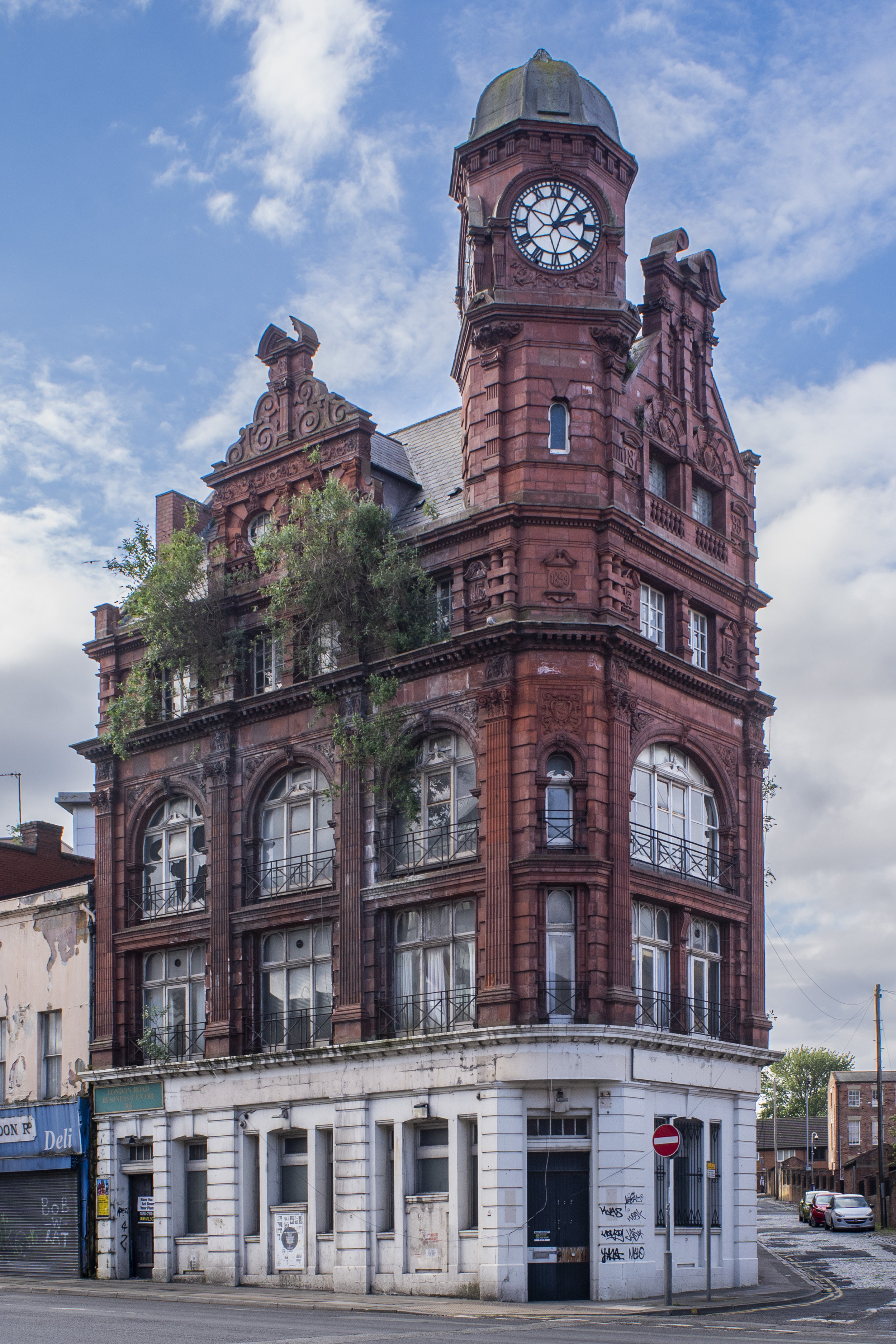 A neglected red brick building with a clock tower.