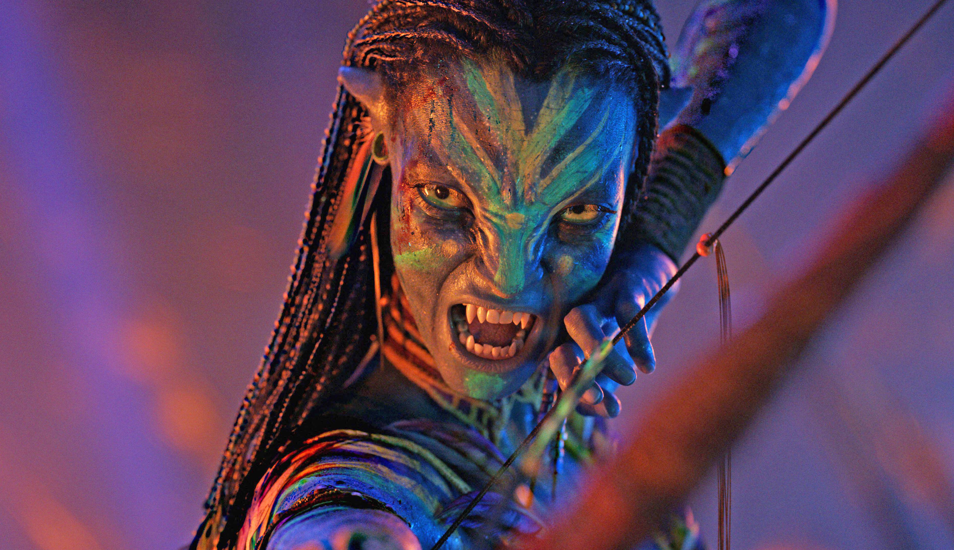 Zoe Saldana as a Na'vi aiming a bow and arrow.