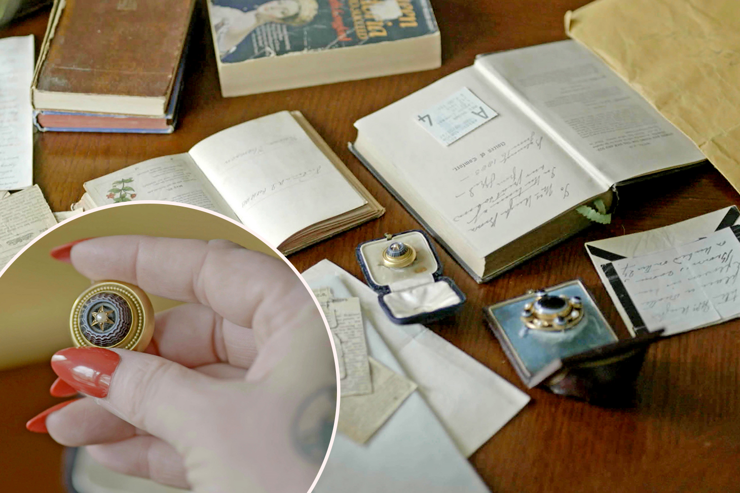 Hand holding antique brooch amongst old books and letters.