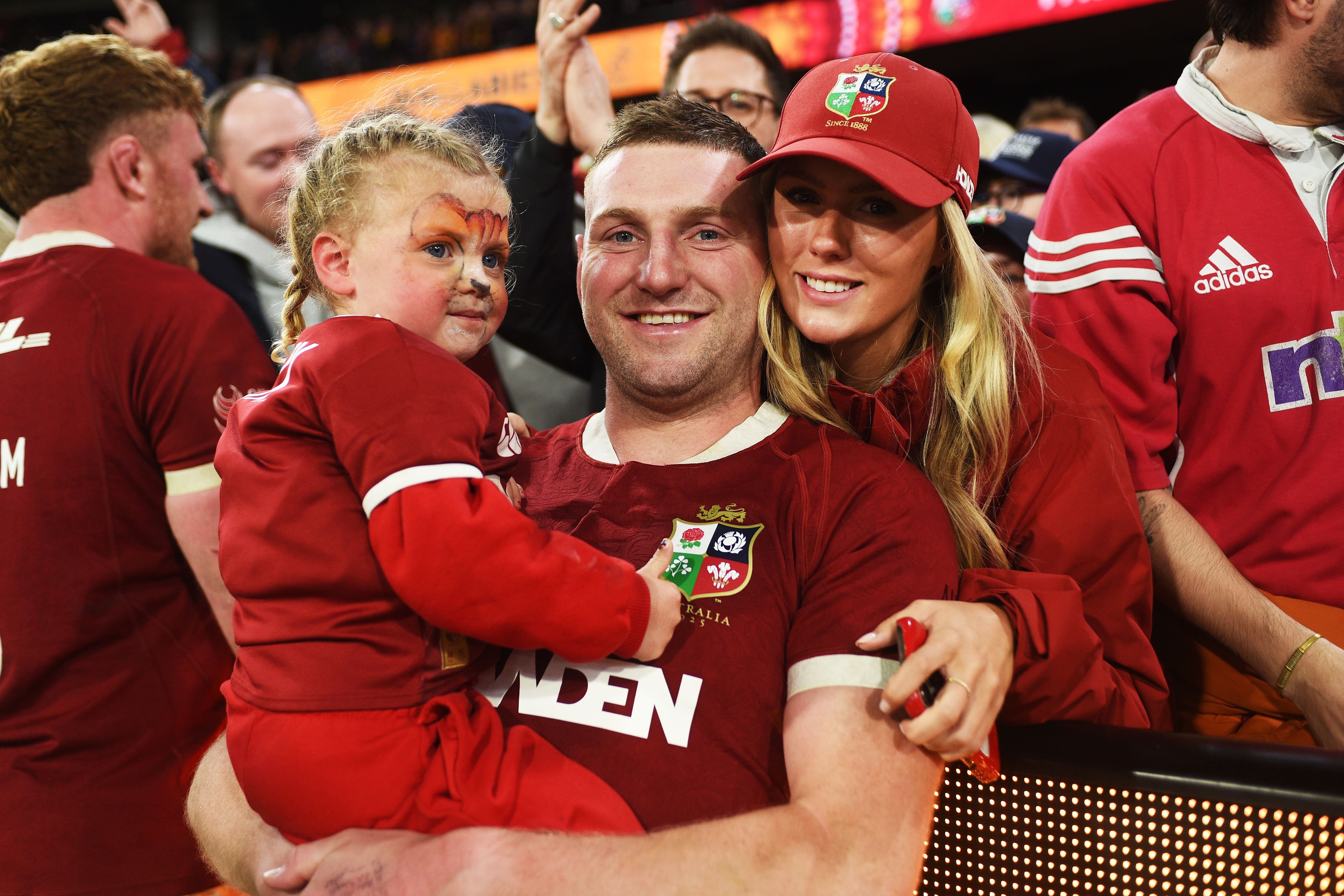 Finn Russell of the British & Irish Lions celebrates a rugby match win with his daughter and partner.