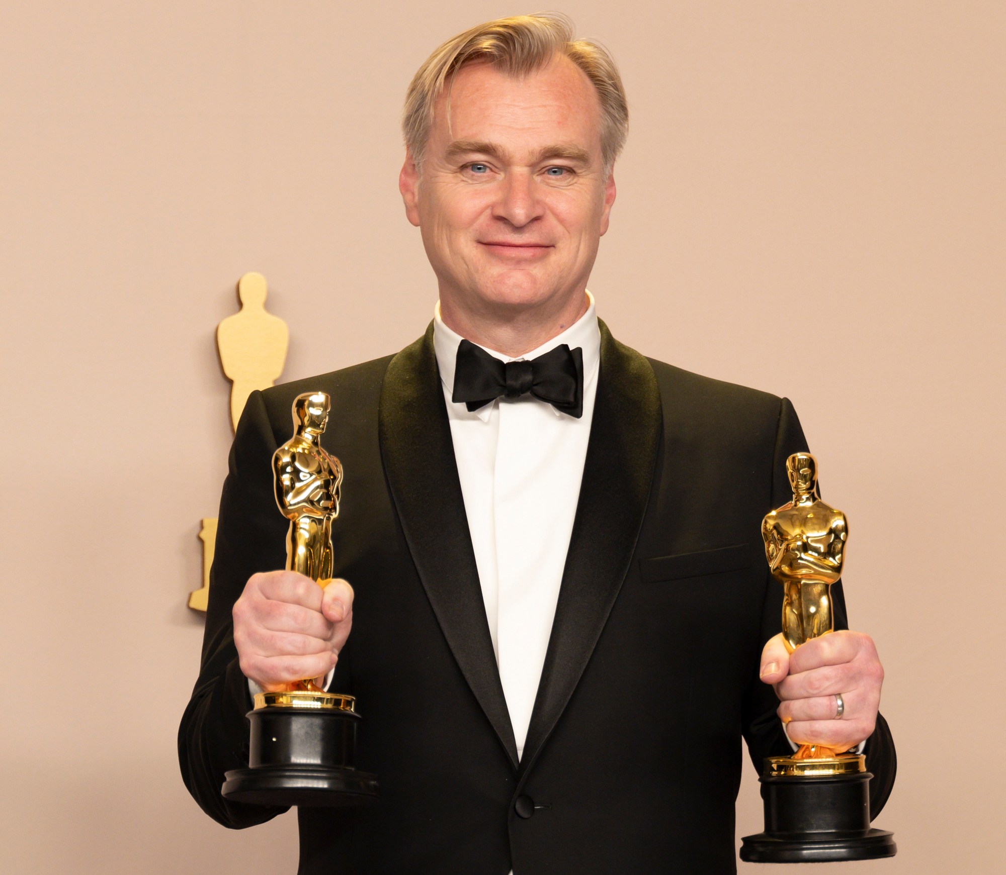 Christopher Nolan holding two Oscars.