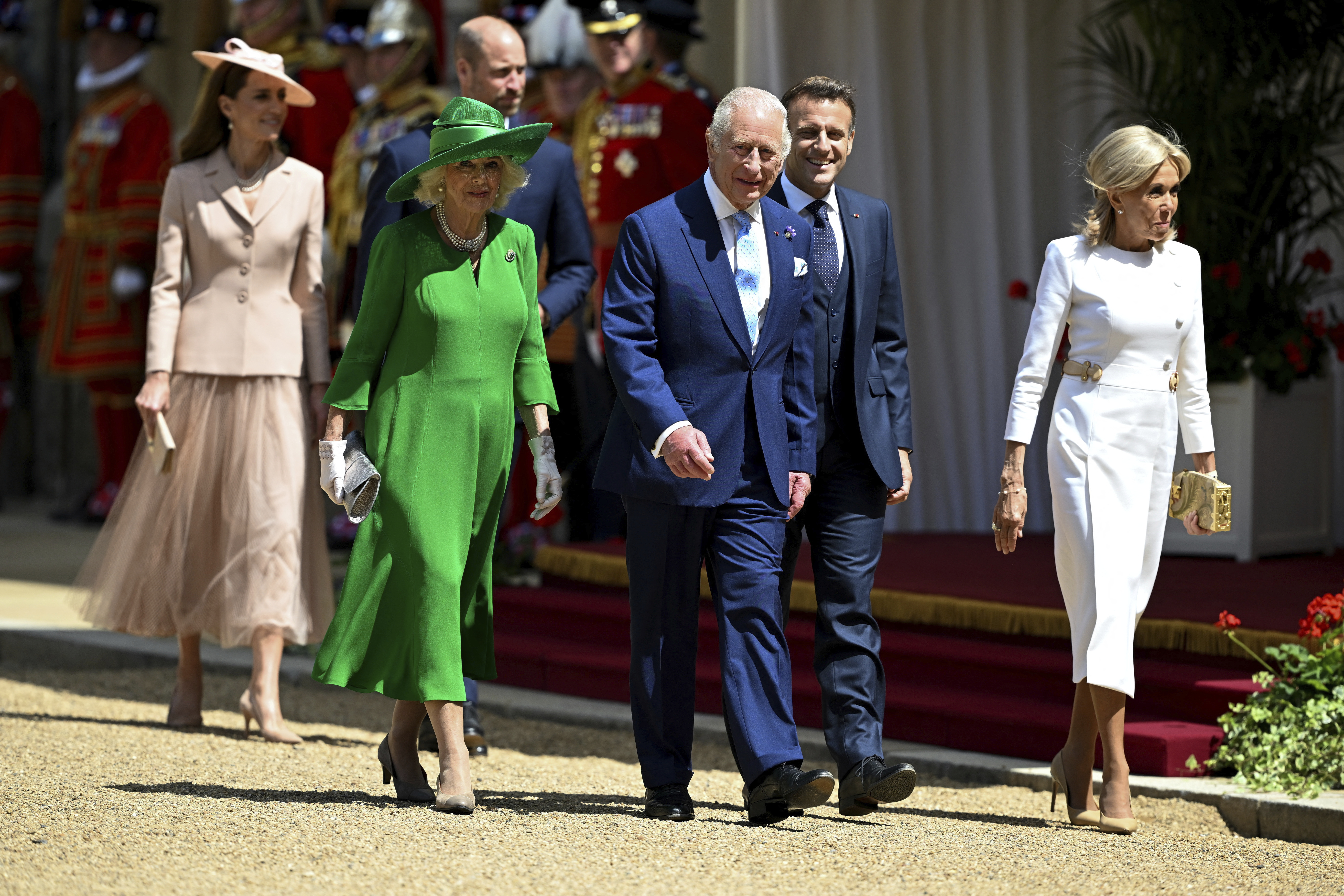 King Charles III, Queen Camilla, Prince William, Kate, Princess of Wales, President Emmanuel Macron, and Brigitte Macron walking together at a welcome ceremony.