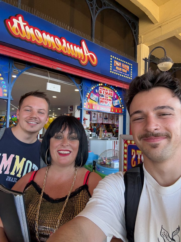 Photo of two men and a woman posing for a selfie in front of an amusement arcade.