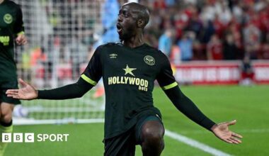 Yoane Wissa celebrates scoring for Brentford with one knee on the ground and his arms outstretched