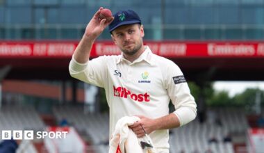 Mason Crance holds a cricket ball to acknowledge fans at the Old Trafford cricket ground