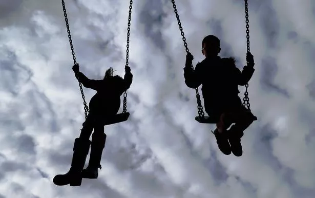Silhouettes of children on playground swings