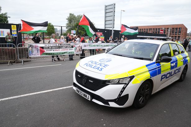 A police car passes protesters outside the 02 Academy in Glasgow before Kneecap's concert