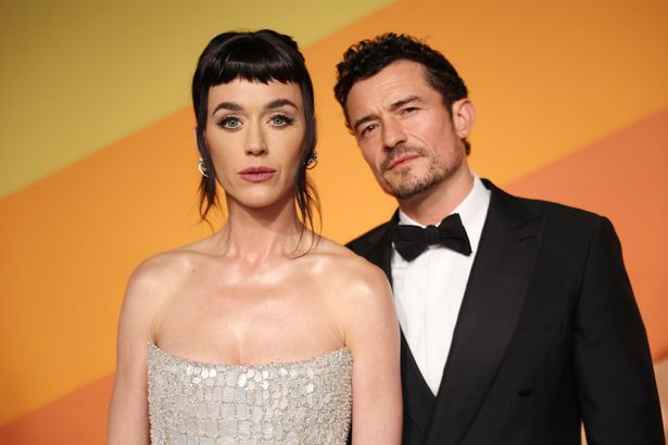 Katy Perry, in a silver dress, and Orlando Bloom, in a black suit.