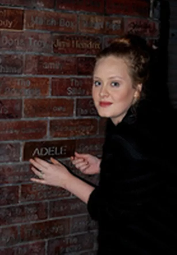 Adele lays a brick in the Cavern wall after performing in 2011 