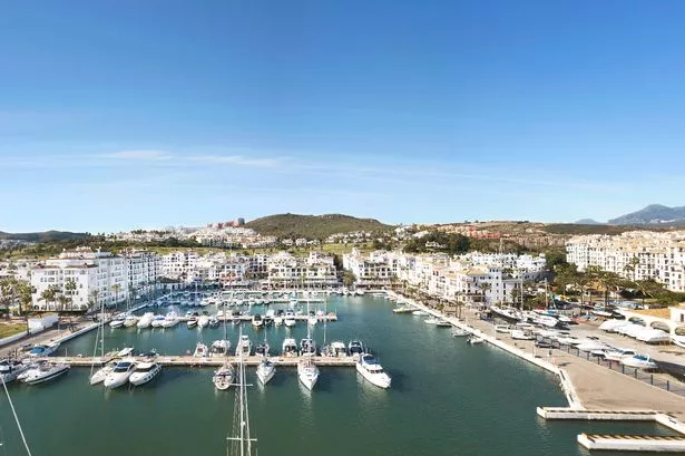 Aerial panoramic view of beautiful "Puerto de la Duquesa" in MANILVA- Malaga SPAIN. Yachts and boats docked in the Harbour. Luxury Apartment Urbanisation and Restaurants . Drone going backward.