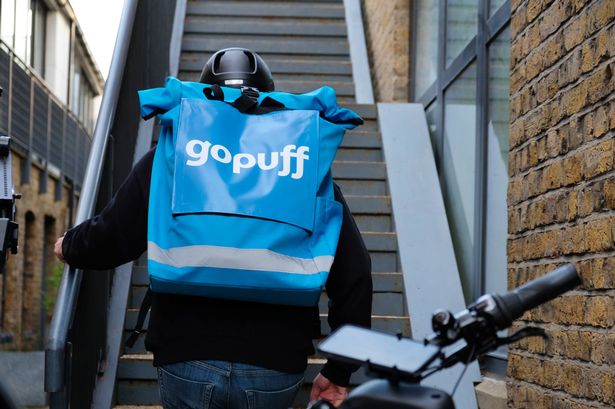 Man on a bike with a blue packpack that says 'Gopuff' in white writing