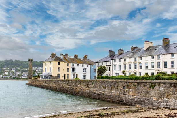 Traditional colorful houses the shoreline of Beaumaris, UK next to the Beaumaris Pier against a dark and white clouded sky