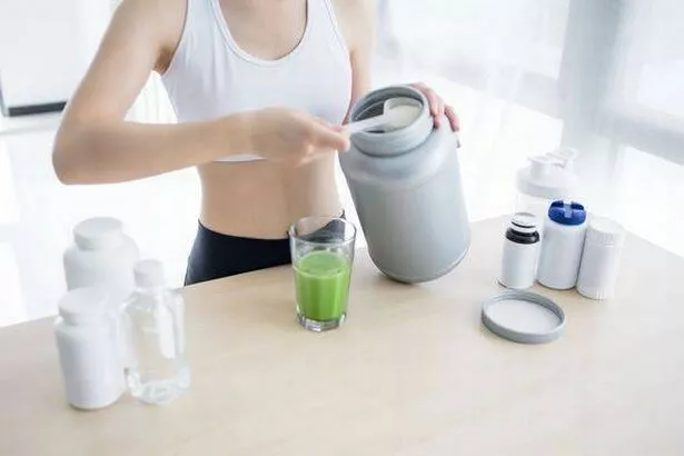 Close-up of a fitness woman pouring Nutritional protein Supplements into shaker.