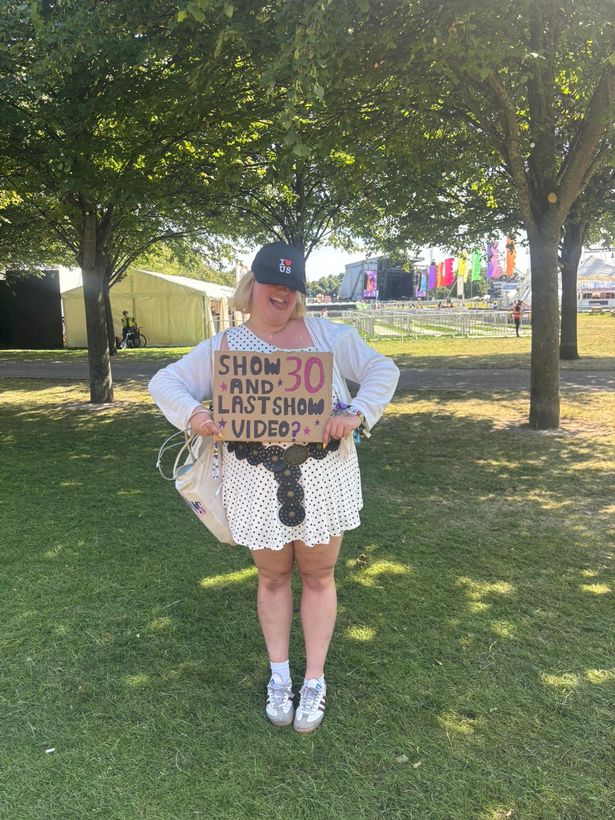 An image of a woman with a blonde bob and black cap, wearing a black and white polka-dot dress, holding up a sign reading "Show and last show video?"