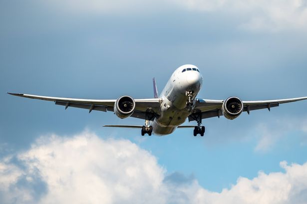 Front view of white 777 commercial flight airplane taking off or landing from the Airport runway with no visible markings or livery. Blue sky sunny back drop with some clouds