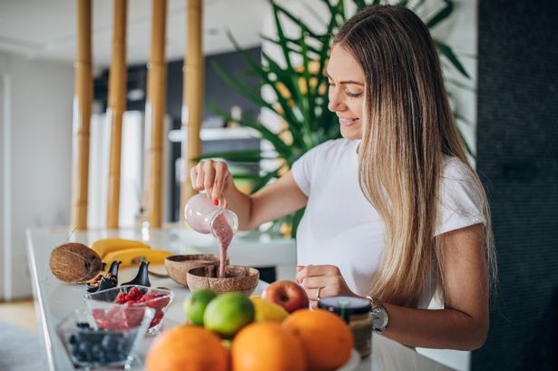woman preparing healthy summer breakfast. Smoothie bowl with fresh fruits, 