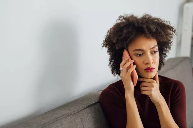 Vusiness woman speaking on her smartphone while sitting at sofa in a living room