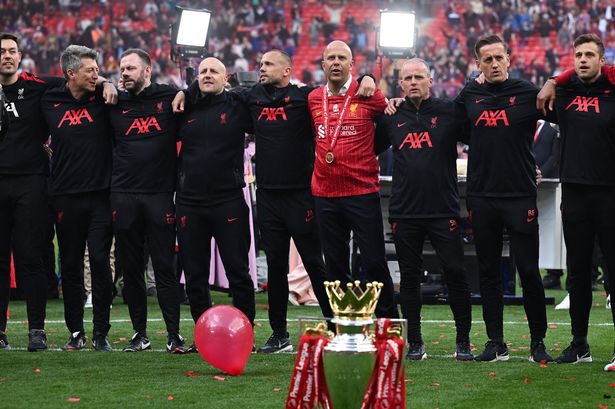 Arne Slot and his coaching staff in front of the Premier League trophy.