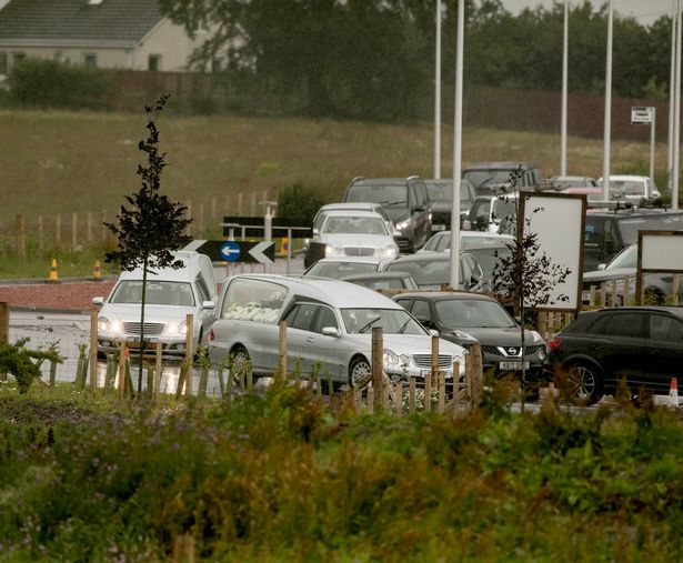 The funeral cars carrying Eddie Lyons and Ross Monaghan arrive. 