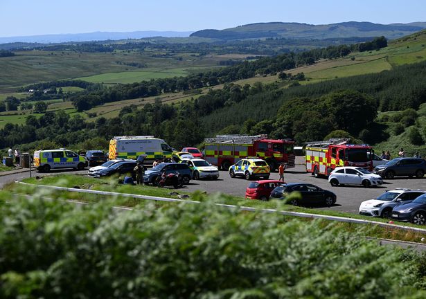 An image of police vehicles, fire engines and ambulances in a car park, with hills visible beyond.