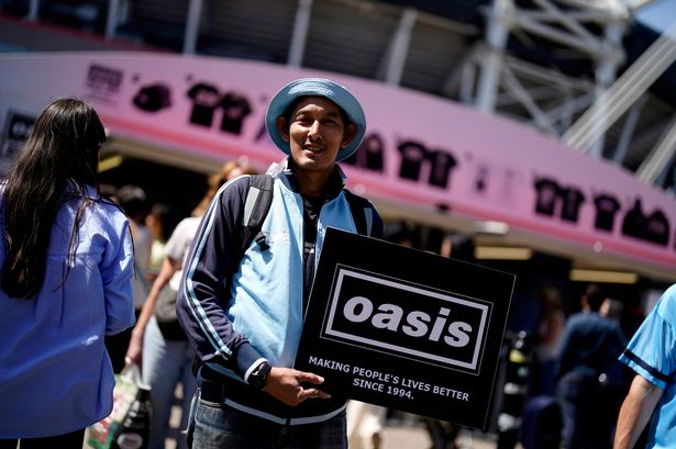 An Oasis fan holds up his sign outside the Principality Stadium, Cardiff, as the band's long-awaited reunion tour kicks off in Wales.