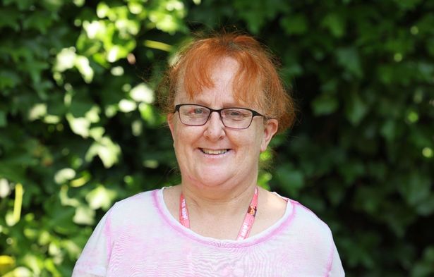 Paula Cartwright smiling in front of the garden at the Wirral Society for the Blind and Partially Sighted