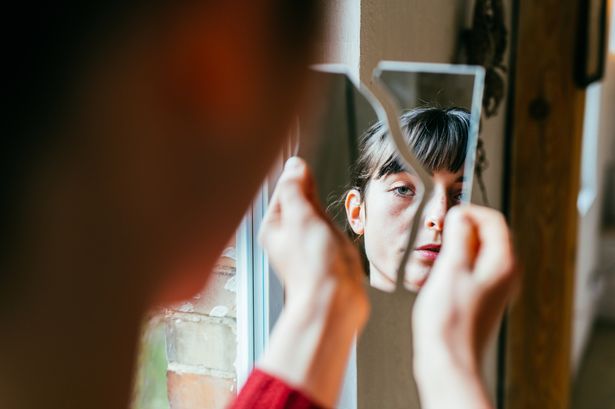 Person staring into a broken mirror