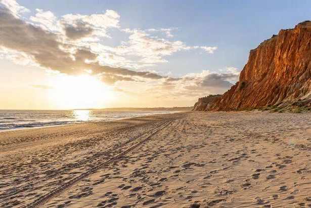 Red cliffs with red soil and breathtaking formations on the wide sandy beach. Praia da Falésia, Algarve, Portugal