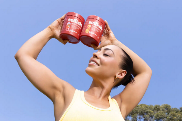 A woman outside holding a pot of Selfish gut powder 
