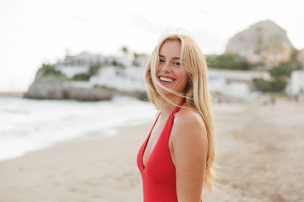 Happy blonde woman wearing red swimsuit enjoying beach vacation
