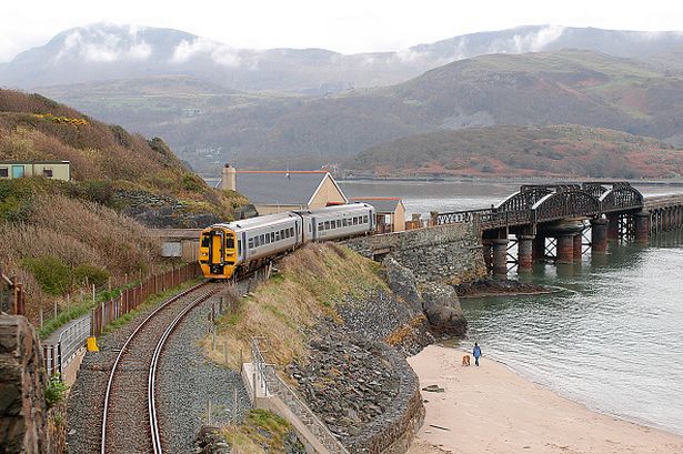 The Mawddach estuary is crossed by the famous Barmouth Bridge, under the shadow of Cadair Idris, to provide a rail link between Machynlleth and Pwhlleli seen being used by a Birmingham - Pwhlleli service as it nears Barnmouth. April 2004. 