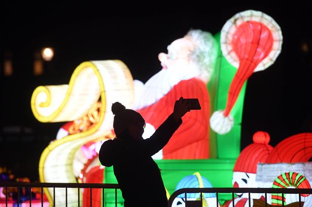 Woman taking selfie in front of light up Santa