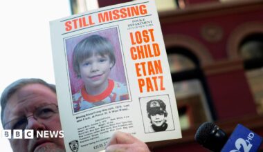 A man holds a missing poster of Etan Patz with blonde hair and text saying 'Lost Child Etan Patz'