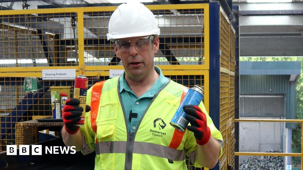 A man pictured in a high vis sleeveless jacket, safety goggles and a white hard helmet holding up two gas canisters. One is yellow and red, the other is blue. He is handling them in red gloves.