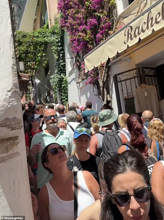 Europe is groaning under a tourism surge. Shocking footage reveal the extent of the crisis, with some streets so crowded that tourists are forced to shuffle shoulder-to-shoulder just to move. Pictured:  A street in Positano, Italy