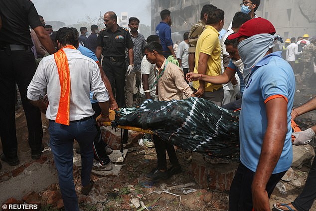 Pictured: People carrying the body of a victim from the crash site after Air India flight 171 crashed in Ahmedabad