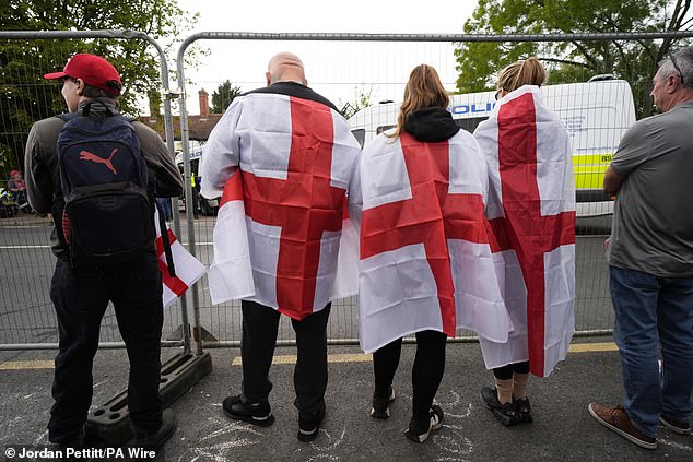 The demonstrations were triggered after Ethiopian man Hadush Kebatu was charged with sexually assaulting a schoolgirl just days after he arrived in Britain. Pictured: three protesters draped in English flags look through the protective fencing