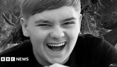 Black and white close-up of Harvey Willgoose, laughing and looking at the camera