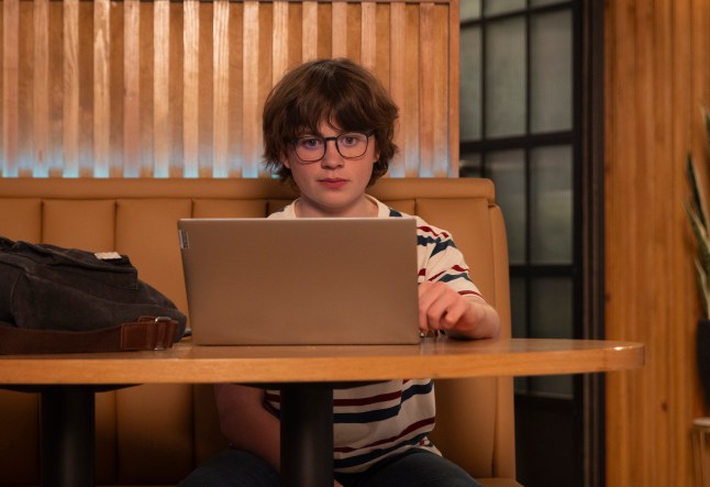 Sam sits at his computer in a booth in the bistro in Corrie
