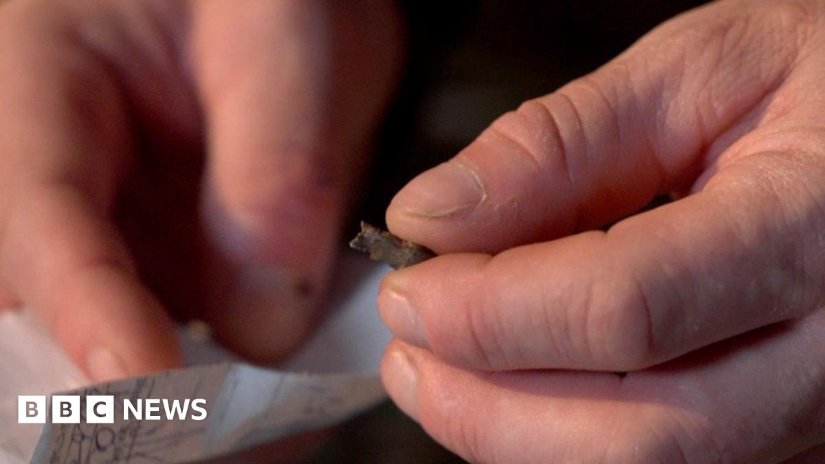Ukrainian serviceman Serhiy Melnyk holds above a scrap of paper a small grey piece of shrapnel once lodged in his heart.