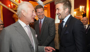 David Beckham greeting King Charles III with a laugh while King Charles III is in the middle of saying something.