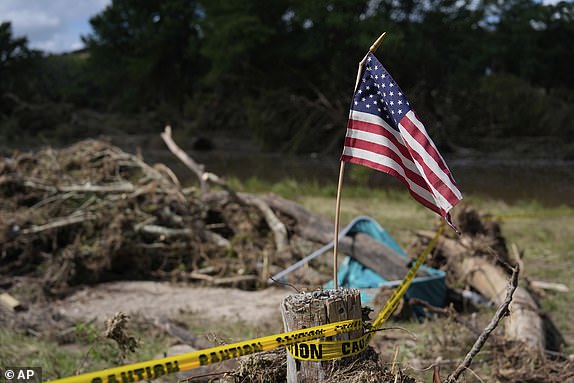 An American flag is placed on a stump in Kerrville, Texas on Tuesday, July 8, 2025. (AP Photo/Ashley Landis)