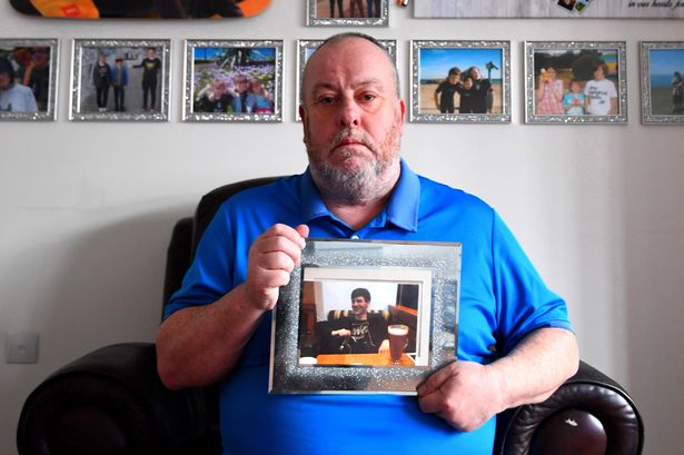 Michael Rainsford Snr, holding a photograph of his son, Mikey Rainsford