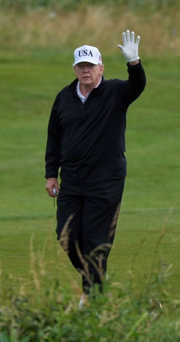 US President Donald Trump waves to photographers from the fairway of his Turnberry golf course in South Ayrshire, Scotland.