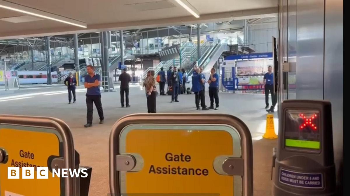 Yellow barriers blocking access to the platforms, with staff in the background.