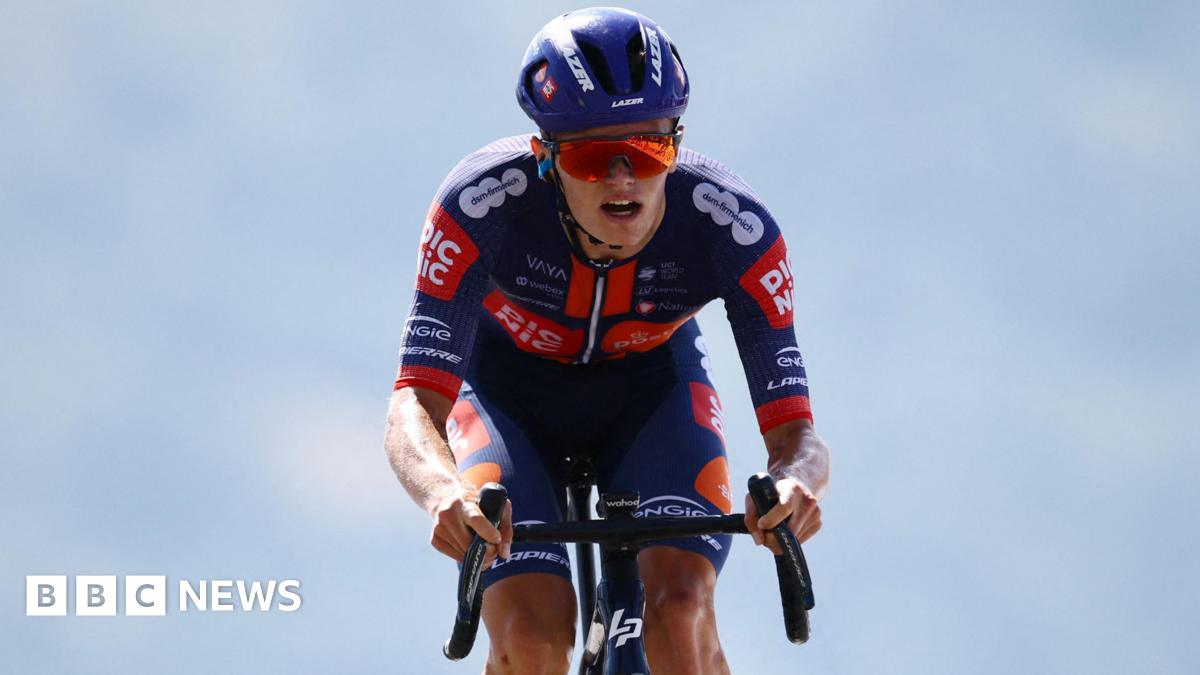 Cyclist Oscar Onley in blue and orange kit with a blue helmet and orange reflective sunglasses
