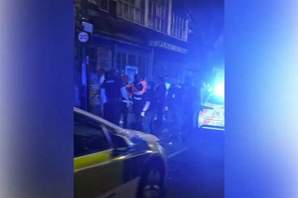 Officers speak to a group on Whitworth Street West before an arrest is made